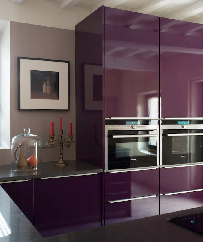 eine violette küche mit einer violetten wand mit einem weißen bilb und mit großen violetten küchenschränken, aubergine farbe, drei rote kerzen, ein haus einrichten