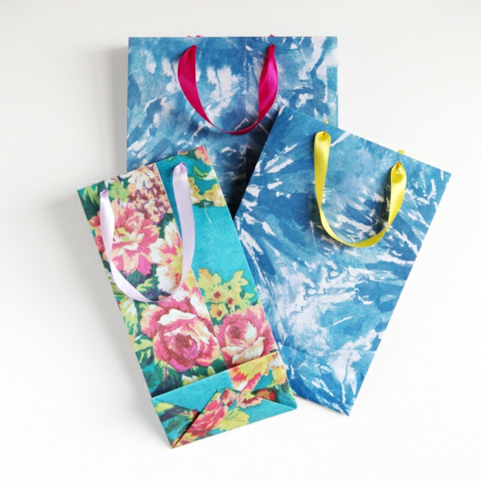drei blaue Tüten, zwei mit abstrakten Motiven, eins mit Blumenmotiven, Geschenktüten basteln