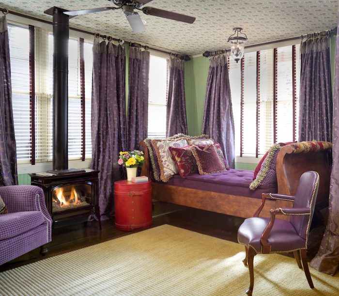 gardinen wohnzimmer, ein gelber teppich und ein boden aus holz und violette soffas und ein wiolettes bett, aubergine farbe wohnzimmer, eine vase mit gelben und pinken blumen