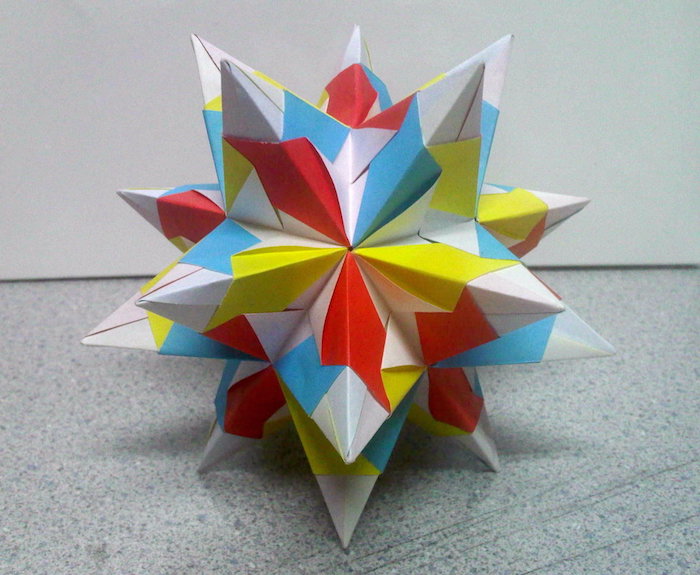 ein großer weißer bascetta stern aus papier und mit blauen, roten, gelben und weißen strahlen aus papier, origami falten, anleitung bascetta stern
