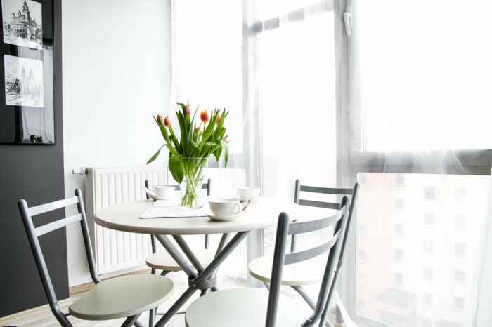 ein runder Tisch, eine Vase voller Tulpen, Grautöne an den Wänden