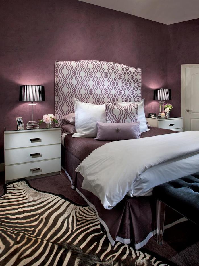 ein schlafzimmer mit violetten wänden und mit einem bett mit weißen und violetten kissen, schlafzimmer aubergine farbe, zwei kleine schwarze lampen und weiße möbel