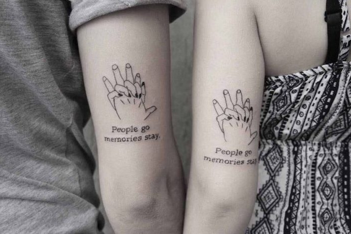 zwei hände mit kleinen schwarzen partnertattoos mit händen mit einem weißen und einem schwarzen nagellack, schrift tattoos