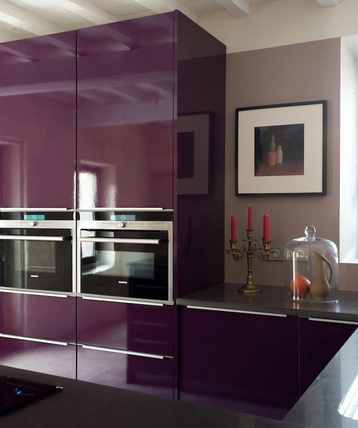 drei rote kerzen und eine violette wand mit einem bild, eine küche einrichten mit großen violetten küchenschränken, aubergine farbe küche