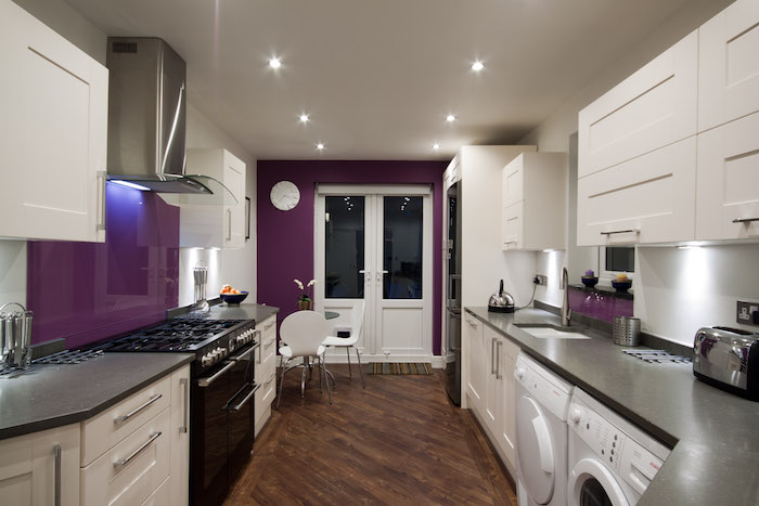 eine weiße waschmaschine und ein brauner biden aus holz, aubergine farbe, eine küche mit violetten wänden und mit weißen küchenschränken, farbe aubergine kombinieren