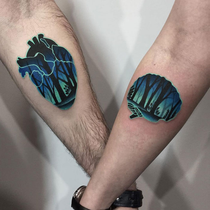 eine hand mit einer schwarzen uhr und mit einem tattoo mit einem blauen gehirn und mit einem wald mit schwarzen bäumen, paar tattoo, herzen tattoo mit bäumen 