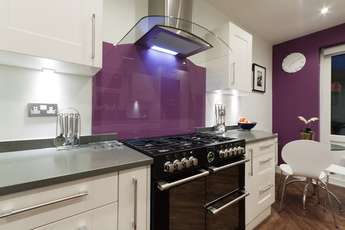 eine küche mit weißen küchenschränken und mit einer violetten wand, ein weißer tisch und ein weißer stuhl, farbe aubergine kombinieren