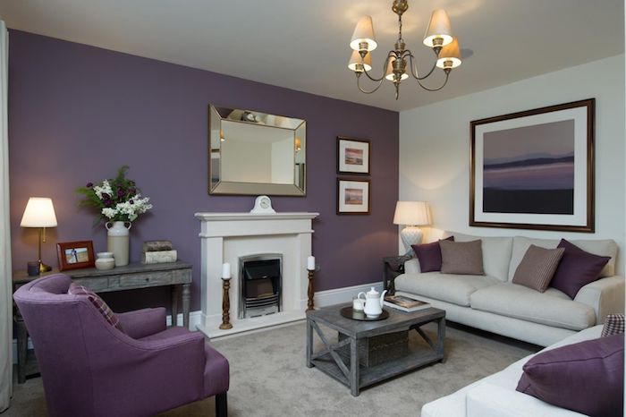 ein großes wohnzimmer mit einer weißen wand mit einem großen violetten bild mit einem schwarzen bilderrahmen, weiße und violette sofas mit kissen, aubergine farbe wohnzimmer einrichten