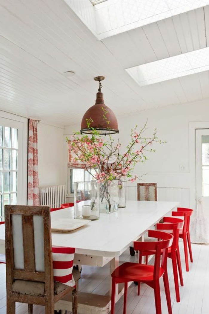 farbenfrohe esstisch deko auf weißem tisch, rote stühle und rote blumen in der vase