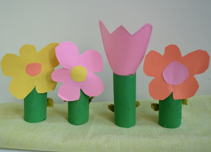 eine Wiese als Bastelideen mit Klopapierrollen für kleine Kinder, rosa Tulpe und andere Blumen