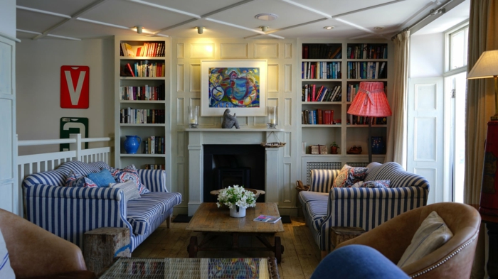 zwei blaue Sofas mit Streifen, weiße Regale, ein Tisch aus Holz, schöne Wohnzimmer