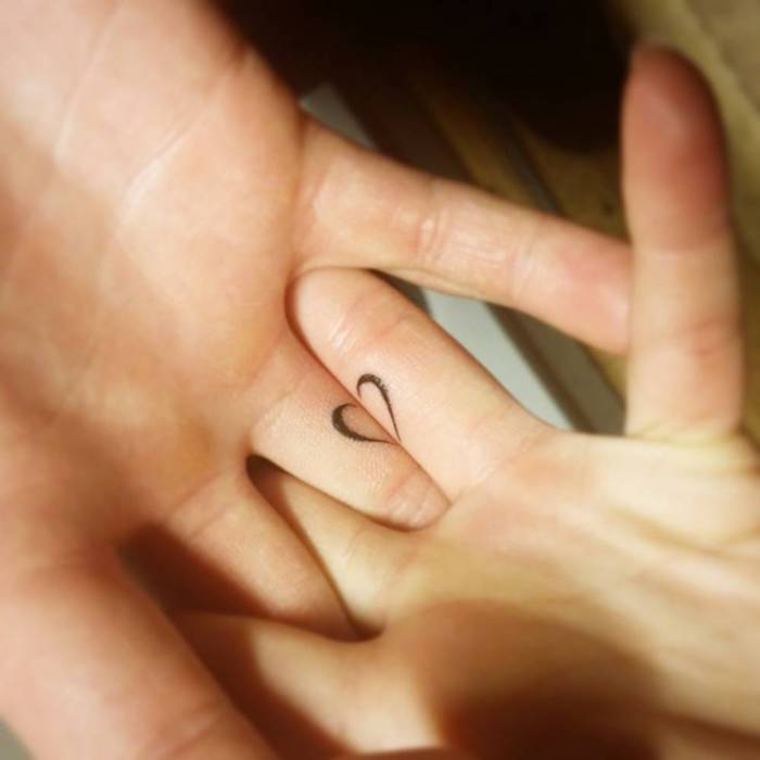 zwei hände mit kleinen schwarzen tattoos, die sich ergänzen, tattoos für paare, herzen tattoos für paare