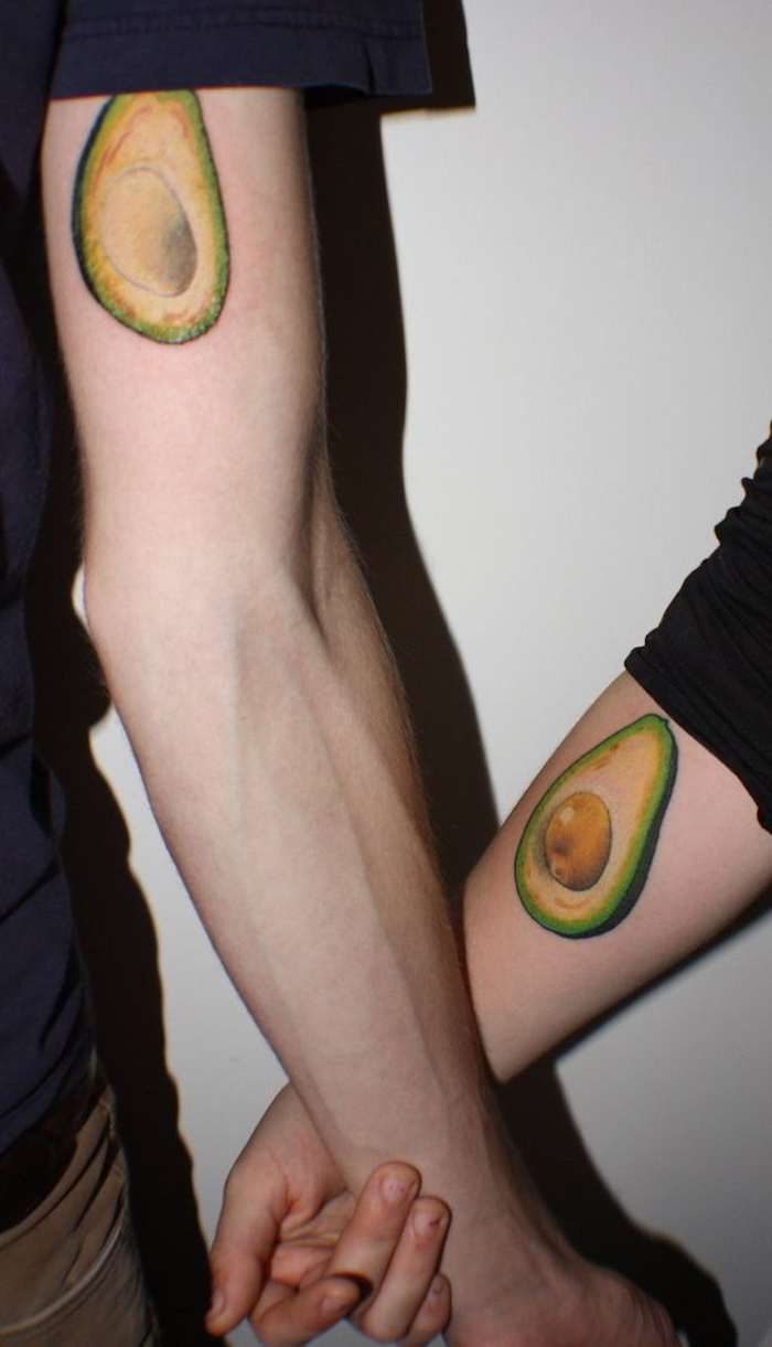 eine weiße wand und zwei hände mit einem grünen avocado tattoo, paar tattoo, zwei tattoos die sich ergänzen