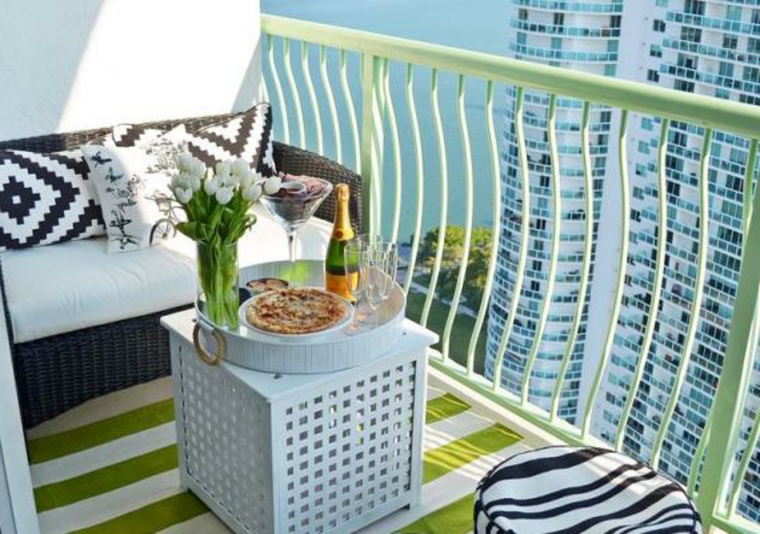 schlichte und stilvolle sitzecke balkon, quadratischer kaffeetisch in weiß mit einem tablett darauf, wein und pizza, weiße tulpen, deko ideen, kissen schwarz und weiß