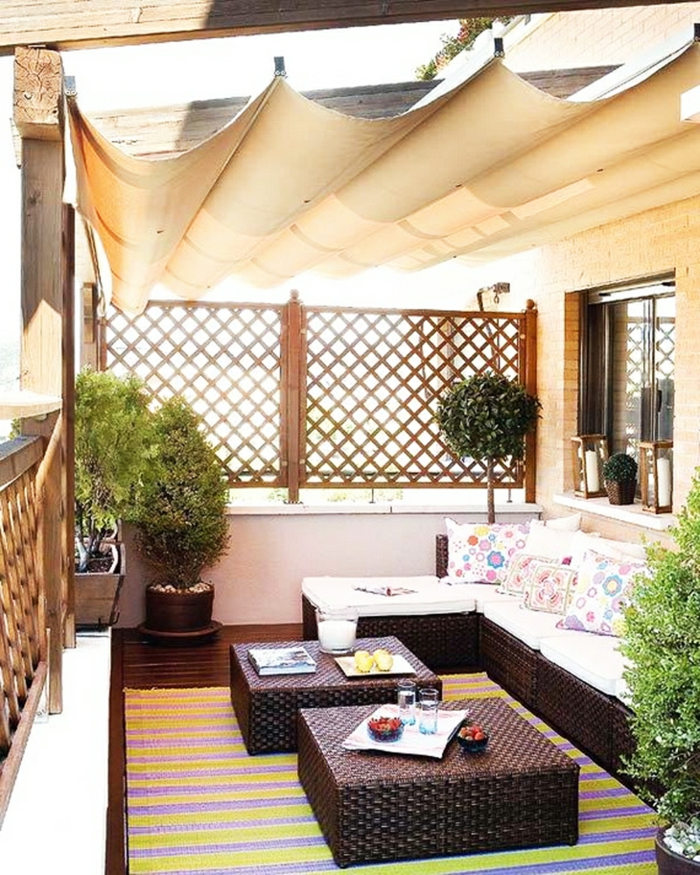 bedeckte sitzecke balkon, gemütlich mit einem rattan sofa und sessel, tisch, kleiner zaun, sichtschutz, sonnenschutz für entspannte momente zu jeder zeit