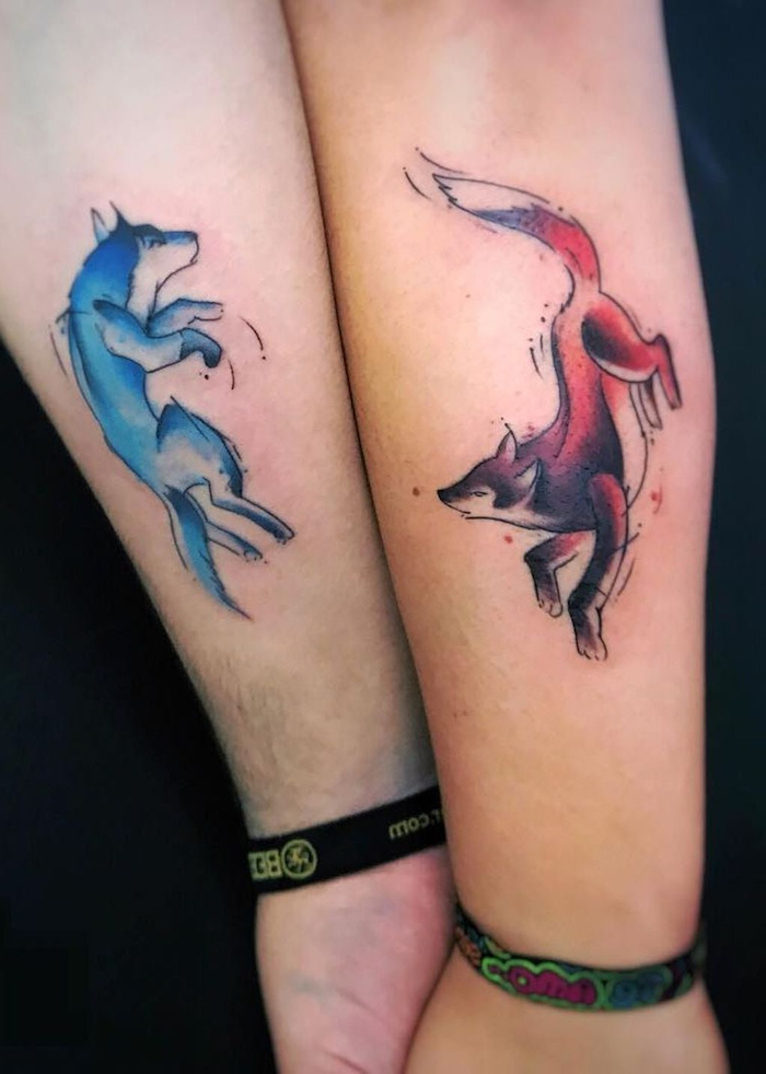 eine hand mit einem tattoo mit einem roten fuchs, tattoos für paare, ein mann mit einem partnertattoo mit einem blauen wolf