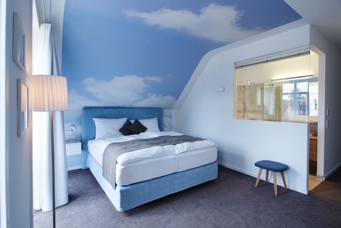 Schlafzimmer Einrichtung, blaues Boxspringbett, Wandfarbe Himmel und Wolken