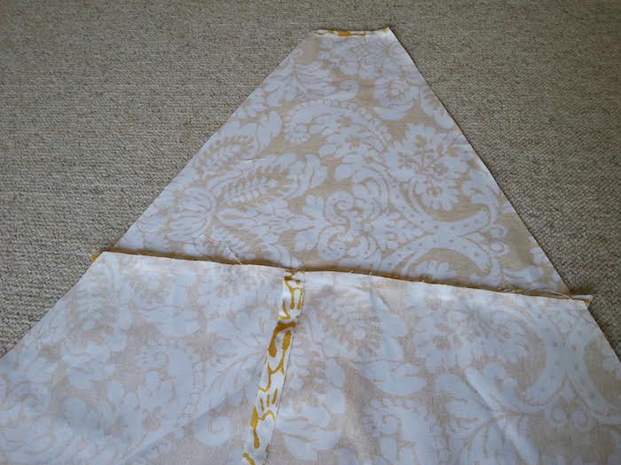 ein großes dreieck aus drei teilen aus einem gelben stoff mit vielen weißen blumen und blättern und ein teppich