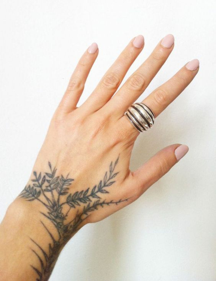 gänseblümchen tattoo, schwarz weiße tattoos, ein großer silberner ring am zeigefinger als ergänzung von dem tattoo