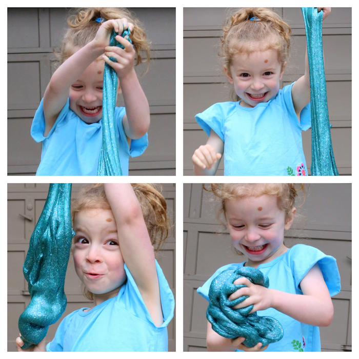 Süßes Mädchen spielt mit Schleim, blauer Schleim mit Glitter, Kind mit blonden Haare, blaues T-Shirt