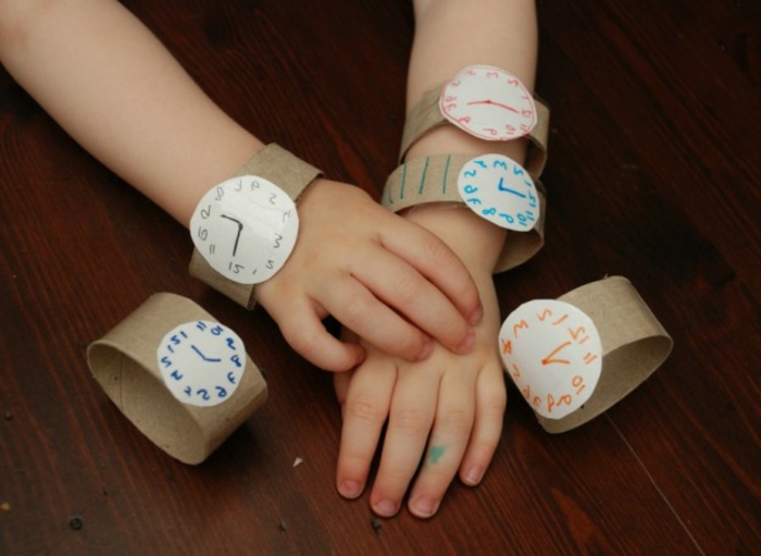 ein Kleinkind mit fünf Armbanduhren, die verschiedene Stunden zeigen, Bastelideen mit Klopapierrollen