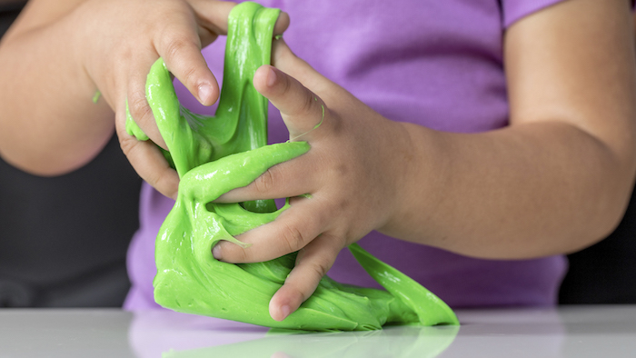 Kind spielt mit grünem Schleim, Rezepte und Anleitungen für selbstgemachten Slime