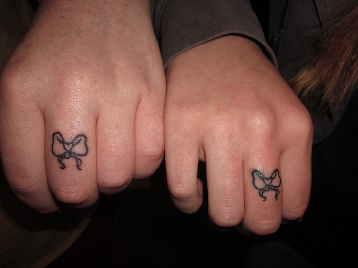 zwei hände mit kleinen schwarzen tattoos mit zwei schwarzen schleifen, tattoos für paare
