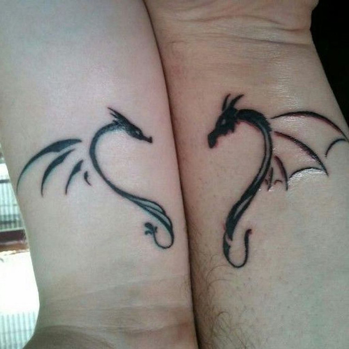 tattoos für paare, zwei hände mit kleinen tattoos am handgelenk und mit kleinen schwarzen fliegenden drachen mit weißen augen und mit kleinen schwarzen flügeln