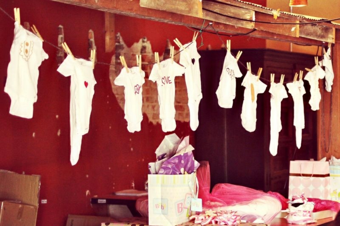 Babyparty Ideen, kleine Klamotten in weißer Farbe mit liebevollen Aufschriften