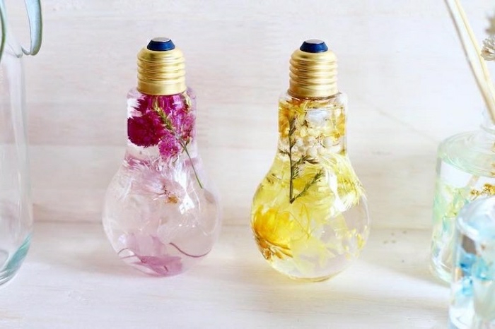 einfache bastelideen in glühbirnen, gelbe blumen und rosarote blumen in wasser in birnen stecken, kreative dekoidee