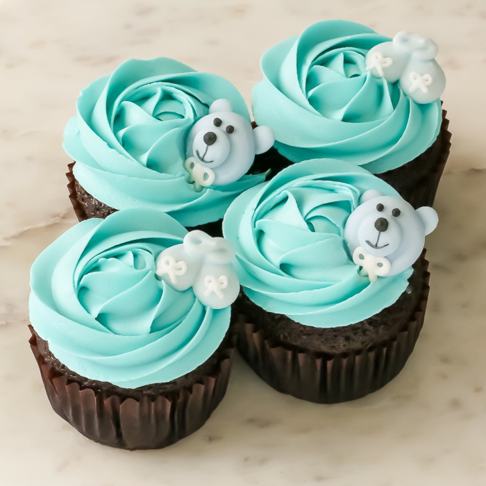 blaue Cupcakes mit Bären und kleine Schuhchen, Babyparty Ideen, etwas Süßes zum Naschen