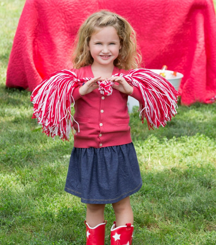 DIY Cheerleader Pompons von einer kleinen Prinzessin mit blondem Haar, Pompons in weißer und roter Farbe