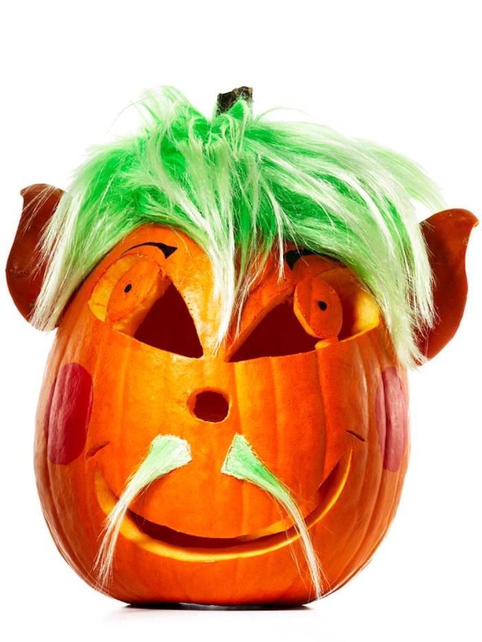 ein oranger halloween kürbis mit einem grünen haar und schnurrbart und großen orangen augen, halloween kürbis schnitzen, lustige kürbisgesichter schnitzen