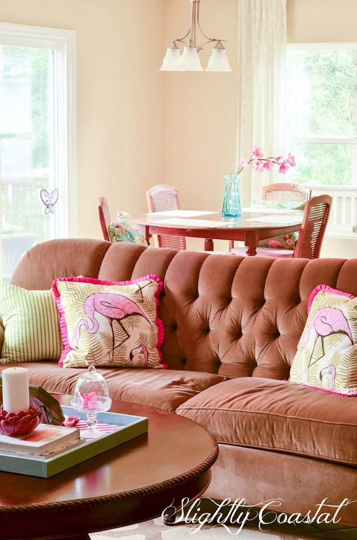 eon wohnzimmer mit einem braunen sofa mit kleinen kissen mit pinken flamingos und ein tisch aus holz und eine blaue vase, wohnzimmer deko ideen