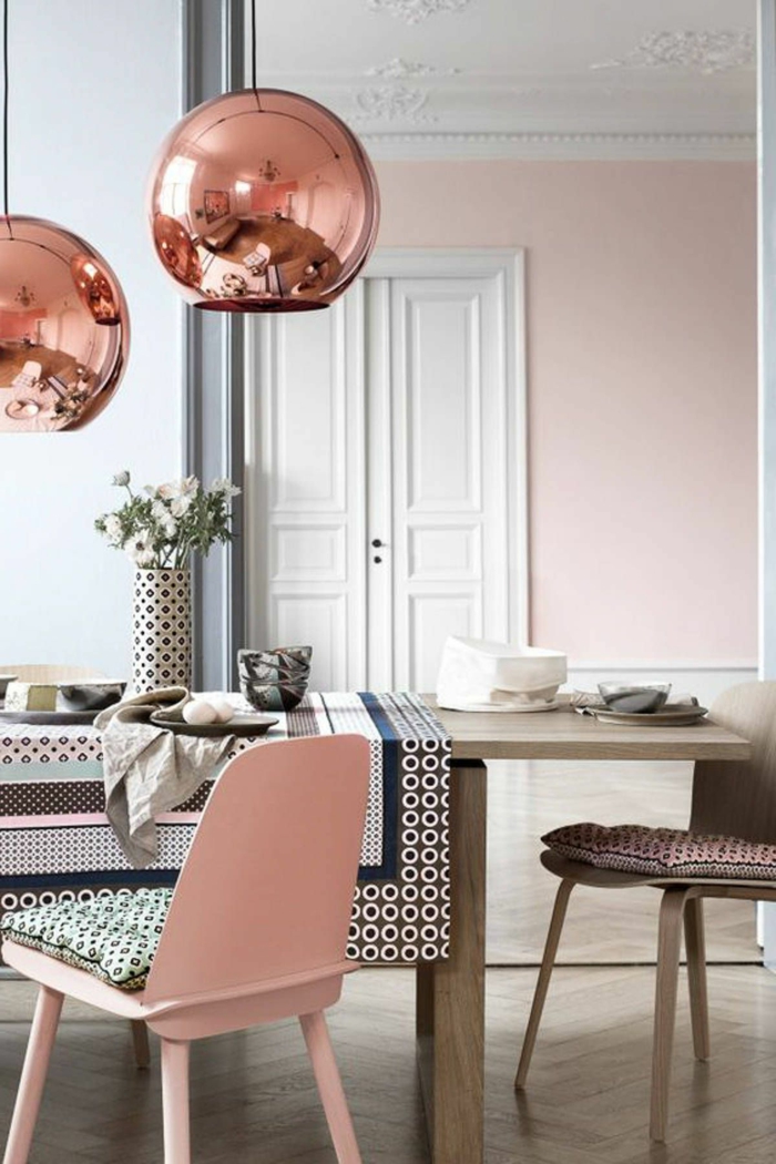 altrosa Wandfarbe, ein kleiner Tisch mit bunter Decke, zwei hängende runde Lampenschirme 