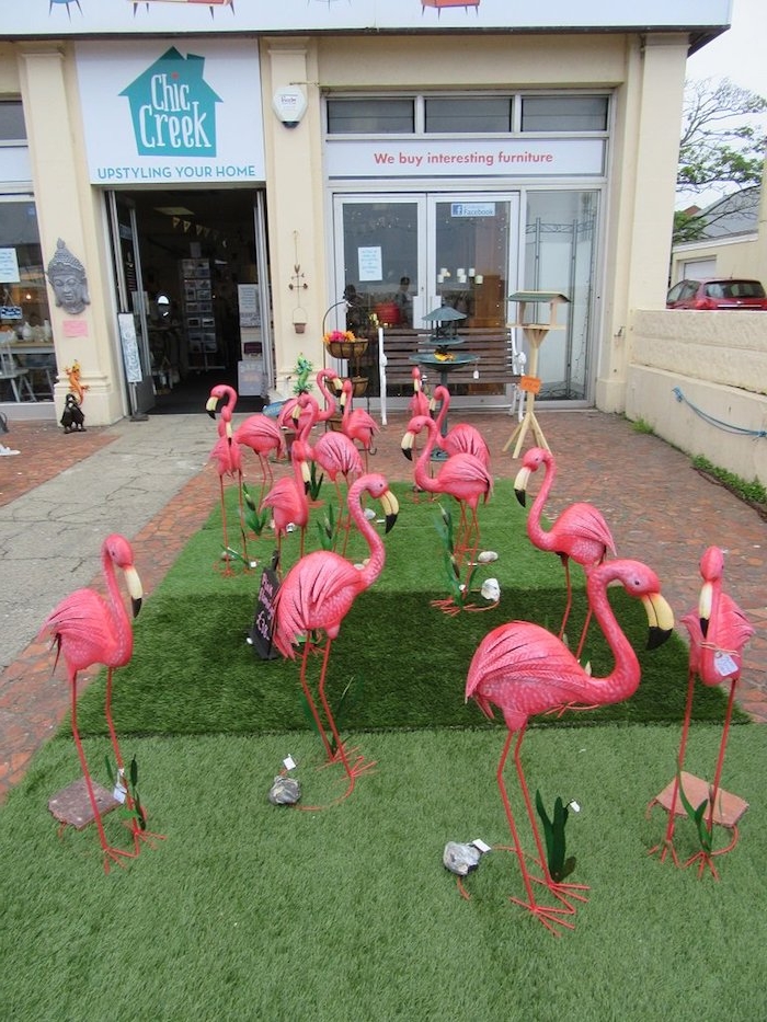 ein gelbes haus und ein grüner rasen und viele dekorative pinke flamingos und kleine graue steine, flamingo deko ideen 