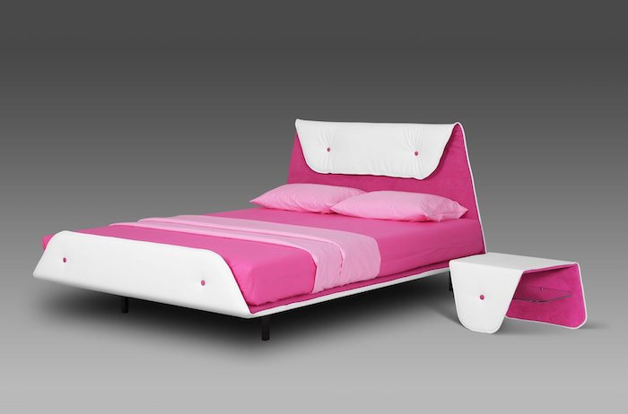 ein schlafzimmer in flamingo style, ein großes weißes bett mit einer pinken decke un d mit zwei pinken kissen, ein kleiner weißer tisch