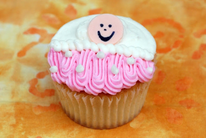 ein Cupcake mit ein lächendes Babygesicht, zwei Arten von Creme, Babyparty organisieren