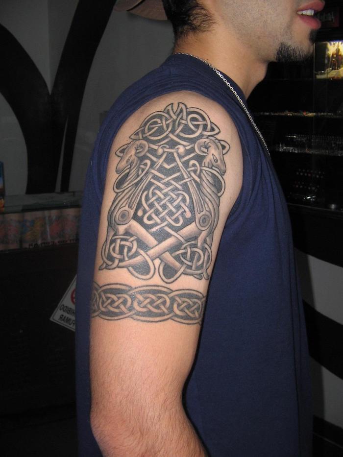 ein mann mit einer hand mit einem schwarzen großen viking tattoo mit weißen totenköpfen, tattoo arm mann