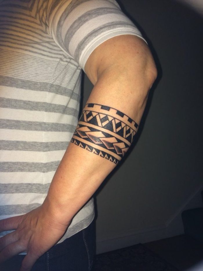 eine hand eines manns mit einer kleinen schwarzen maori tattoo arm mit kleinen schwarzen und weißen zähnen, ein kleiner tattoo arm mann