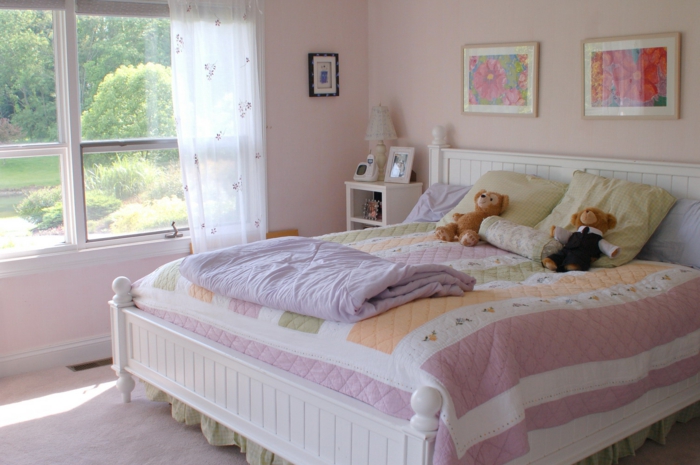 altrosa Farbe, großes Bett, bunte Bettwäsche, Gardinen mit Blumenmuster, zwei Bilder von Blumen