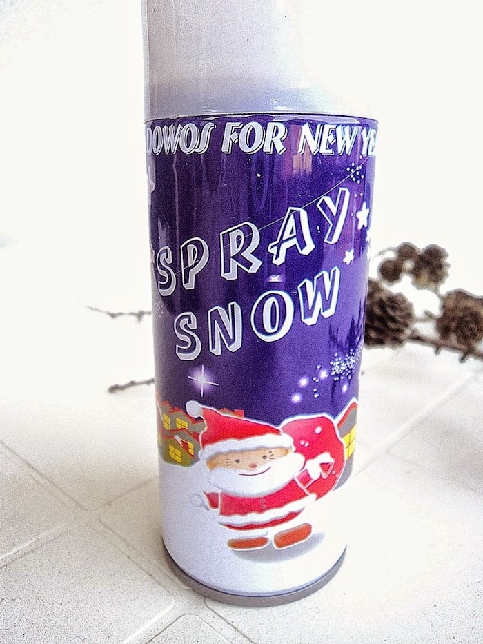 ein boden aus weißen fliesen und ein spray snow mit einem bild mit einem weihnachtsmann und kleinen häusern, äste mit braunen tannenzapfen