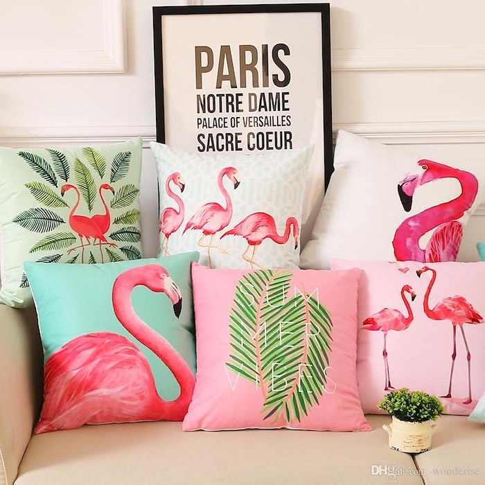 ein sofa mit vielen blauen, pinken, grünen und weißen kissen mit kleinen und großen pinken flamingos und mit grünen blättern, flamingo bilder