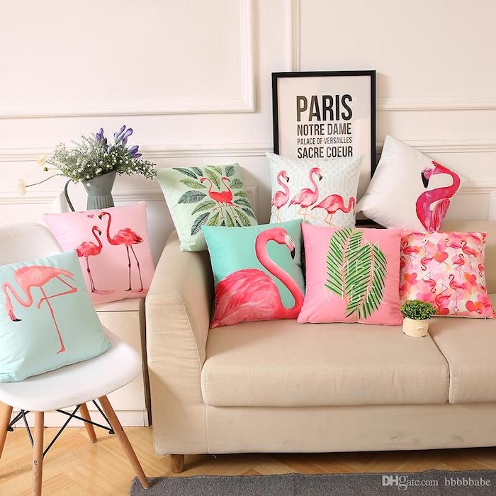 ein weißer stuhl und eine graue vase mit vielen weißen und violetten blumen mit grünen blättern, viele kleine kissen mit kleinen und groén pinken flamingos und grünen palmen 