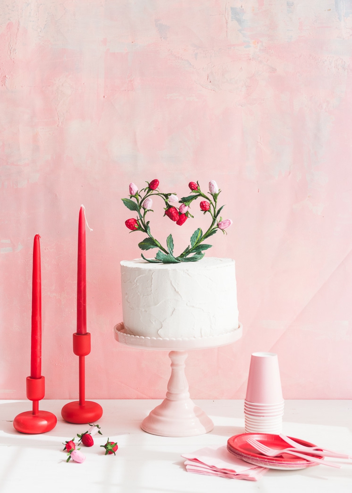 eine weiße Torte mit Blumen als Dekoration, zwei Kerzen und Einweggeschirr