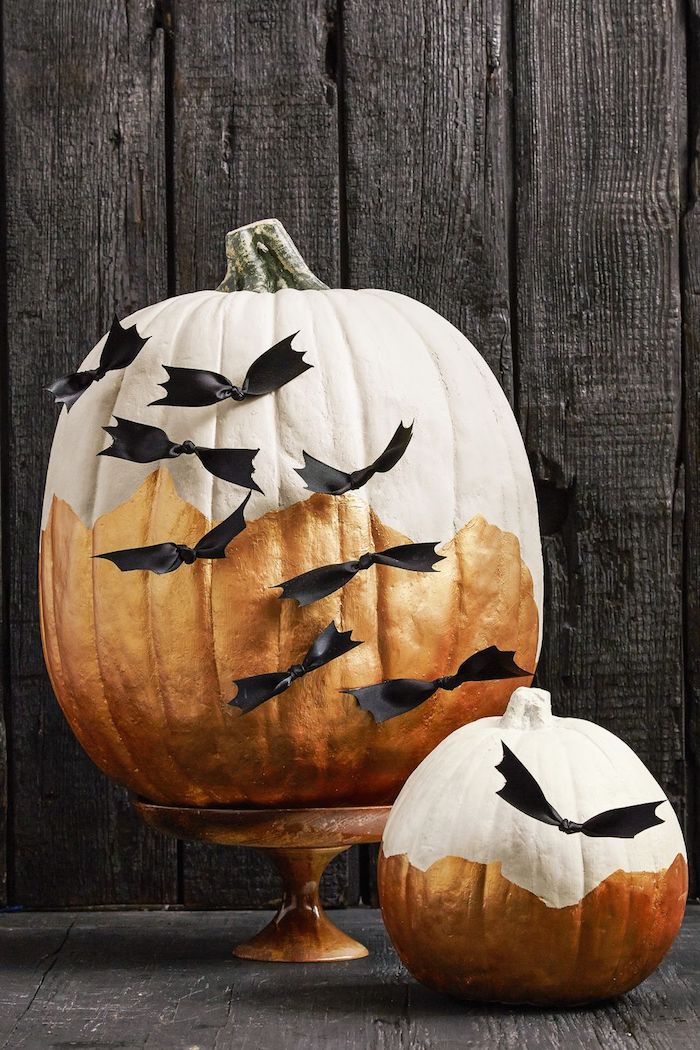 ein großer weißer halloween kürbis mit vielen kleinen schwarzen fliegenden diy fledermäusen aus papier und eine schwarze wand aus schwarzen holzbrettern, fledermaus basteln aus papier
