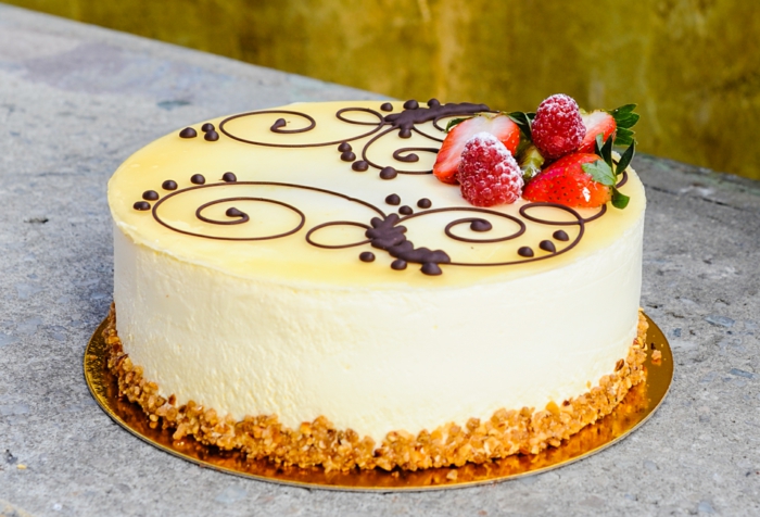 gelbe Creme von einer süßen Torte, Himbeeren und Erdbeeren als Dekoration, einfache Tortenrezepte