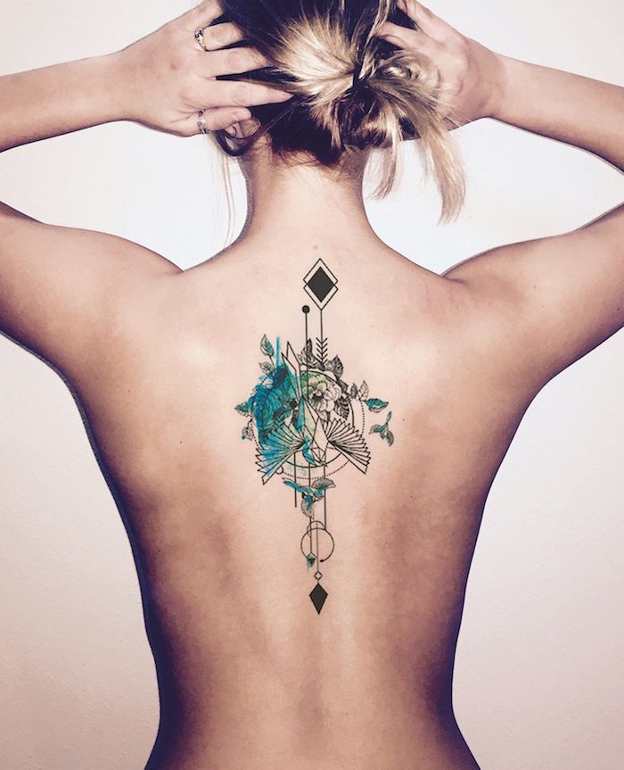 eine junge frau mit einem kleinen watercolor tattoo rücken mit blauen fliegenden vögeln und kleinen blättern, vogel tattoo für frauen 