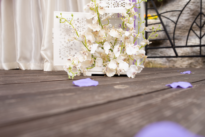 Prachtvolle Dekoration für Hochzeit, weiße Orchideen, lilafarbene Blüten auf dem Boden
