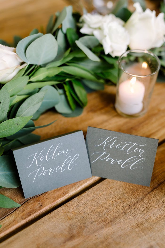 Schöne Idee für Hochzeit Tischdeko, weiße Rosen und Duftkerzen, graue Zettel mit den Namen der Gäste